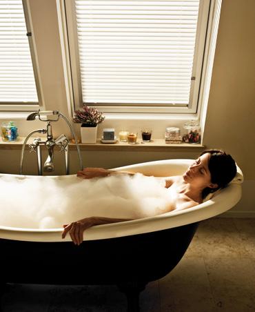 Eine Frau in der Badewanne unter Fenstern